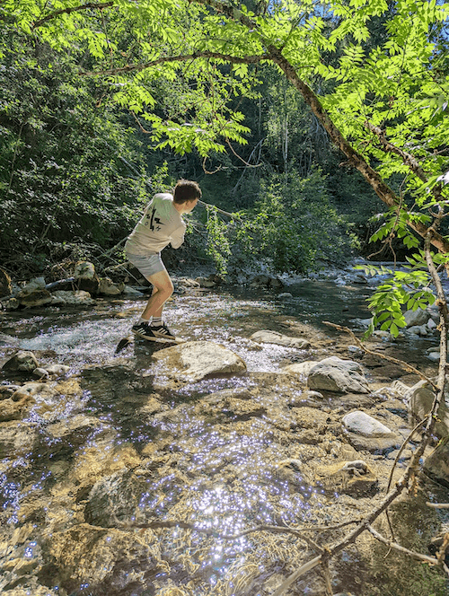 man stood in a stream skipping a stone